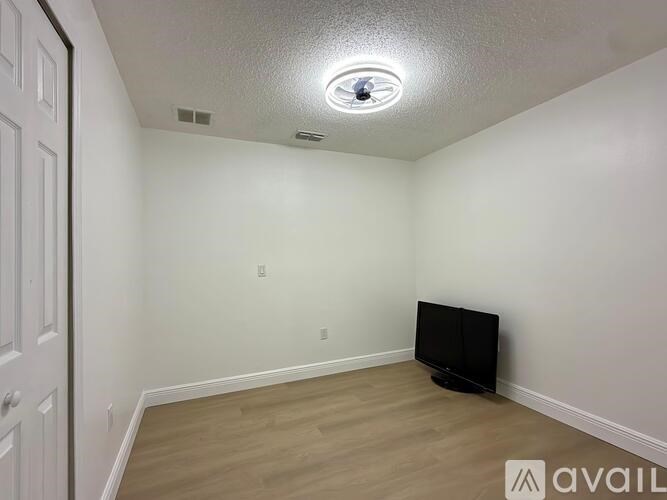 A room with a flat screen TV and wooden flooring.