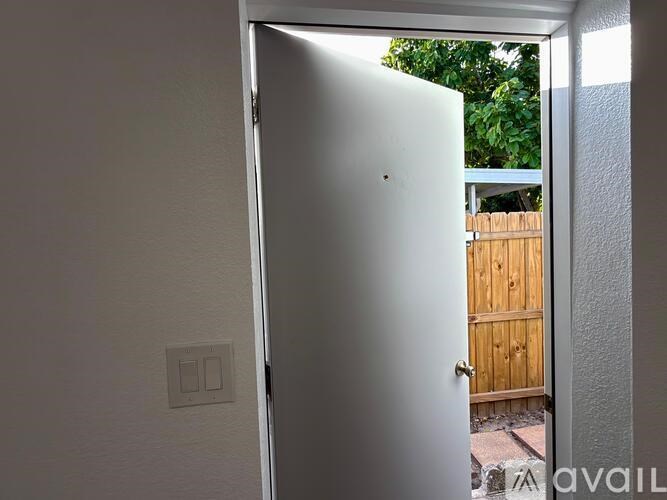 A white refrigerator is in a room with a door open.