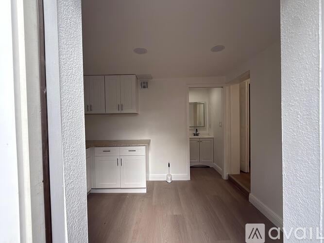 A white kitchen with wooden floors and white cabinets.