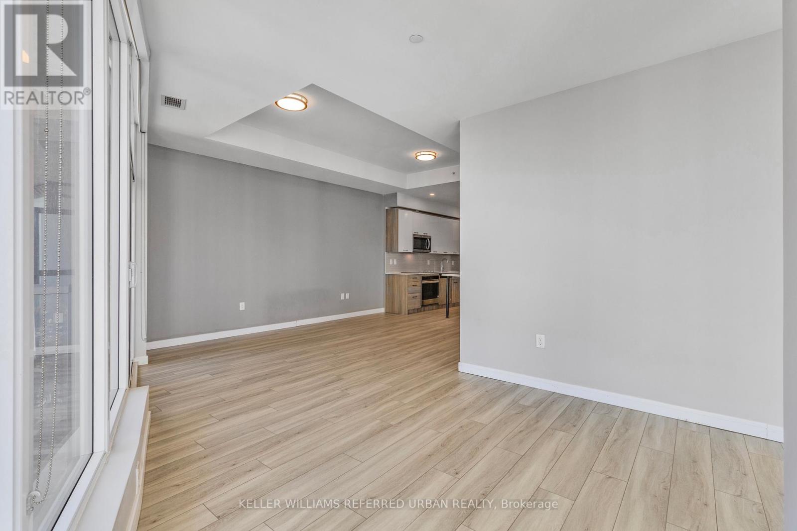 A spacious room with wooden flooring and white walls.