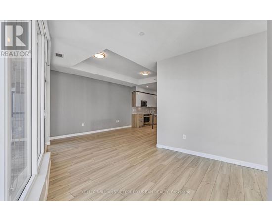 A spacious room with wooden flooring and white walls.