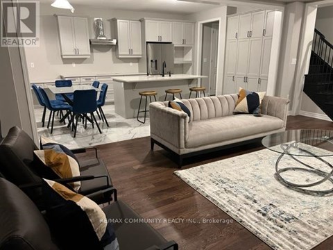 A living room with a couch, chairs, and a dining table.