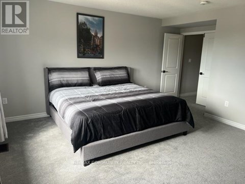 A bedroom with a large bed and a painting on the wall.