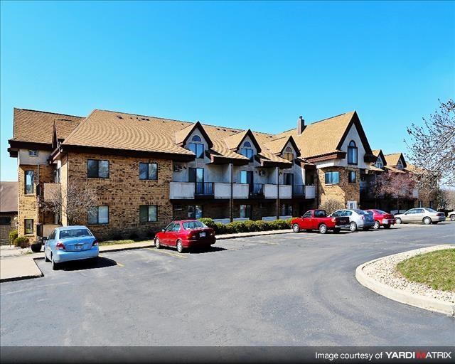 a large apartment building with cars parked in a parking lot