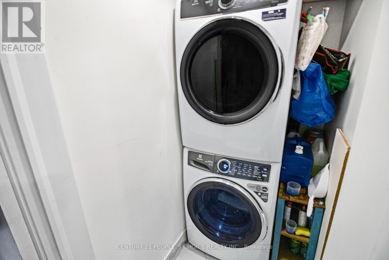 A washing machine is in a small space with a dryer underneath it.