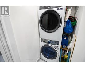 A washing machine is in a small space with a dryer underneath it.