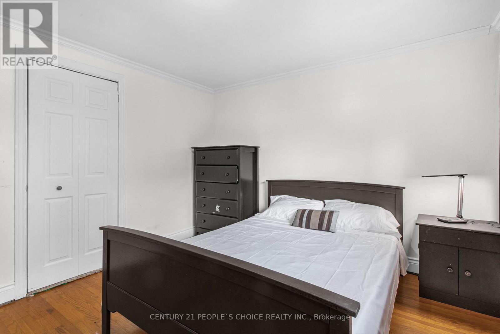 A bedroom with a bed, nightstand, and a cabinet.