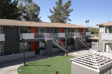 A building with a red door and a balcony with a metal railing.