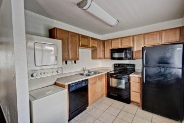 A kitchen with black appliances and wooden cabinets.