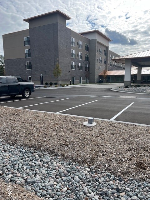 A parking lot in front of a grey building.