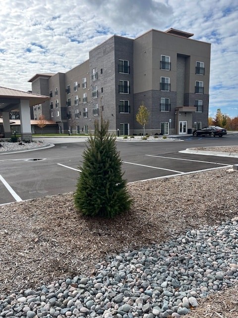A grey building with a parking lot in front.