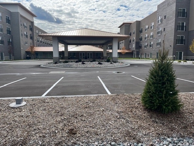 A parking lot in front of a building with a small tree in the foreground.