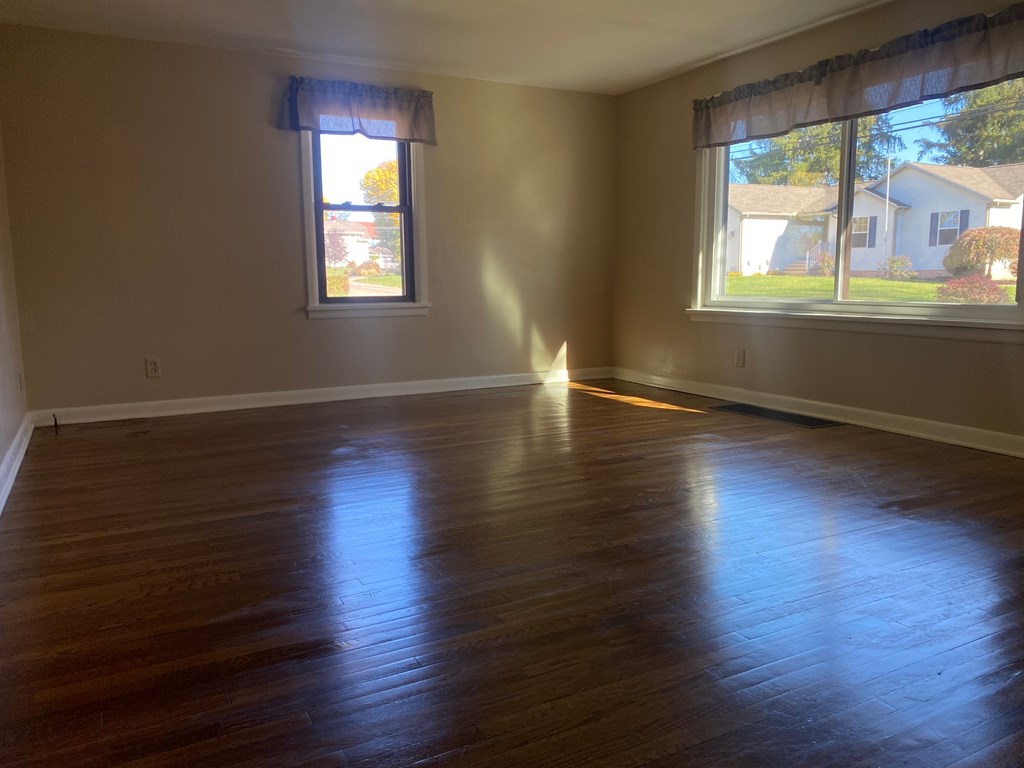 A room with wooden floors and two windows.