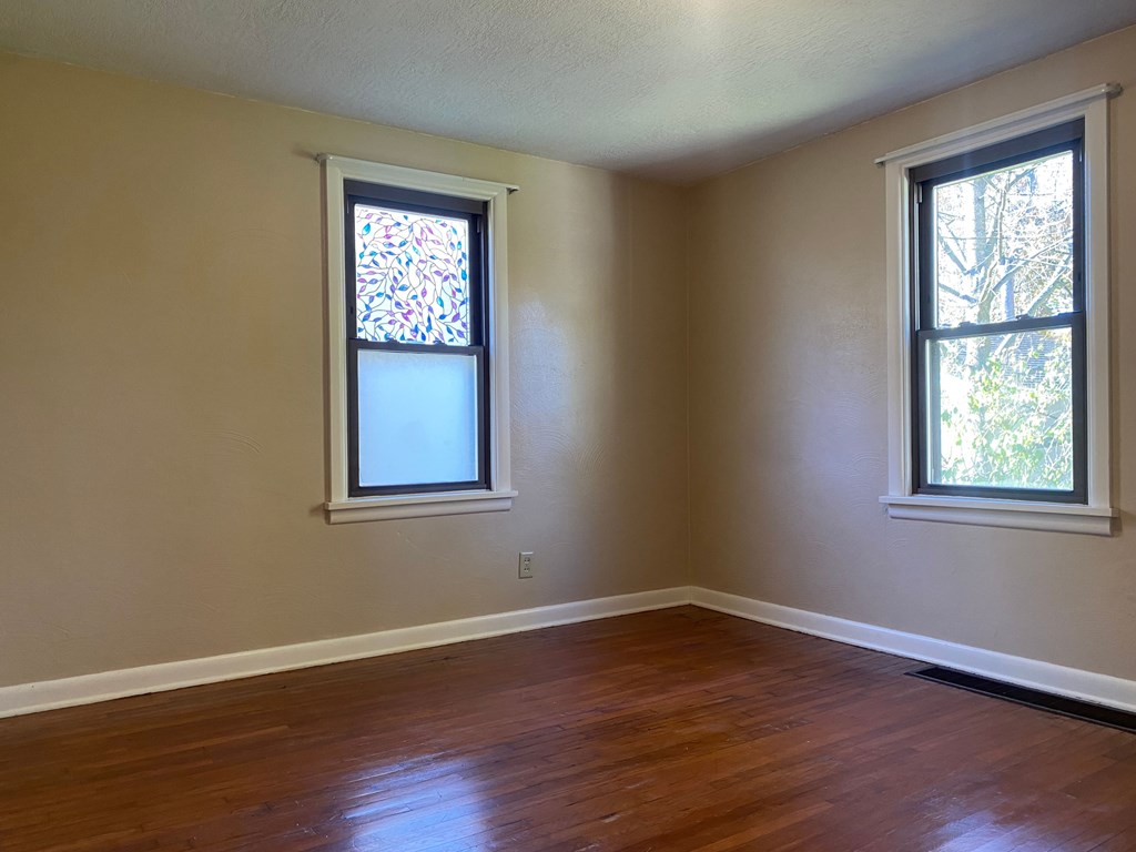 A room with two windows, one of which has a stained glass design.