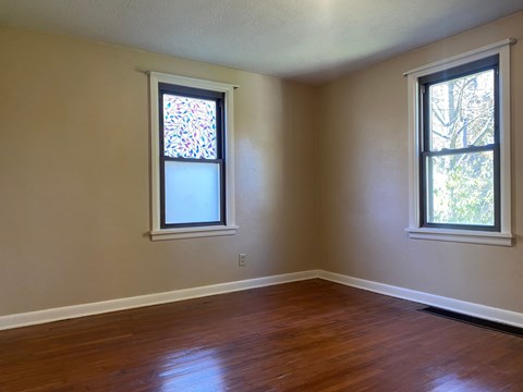 A room with two windows, one of which has a stained glass design.