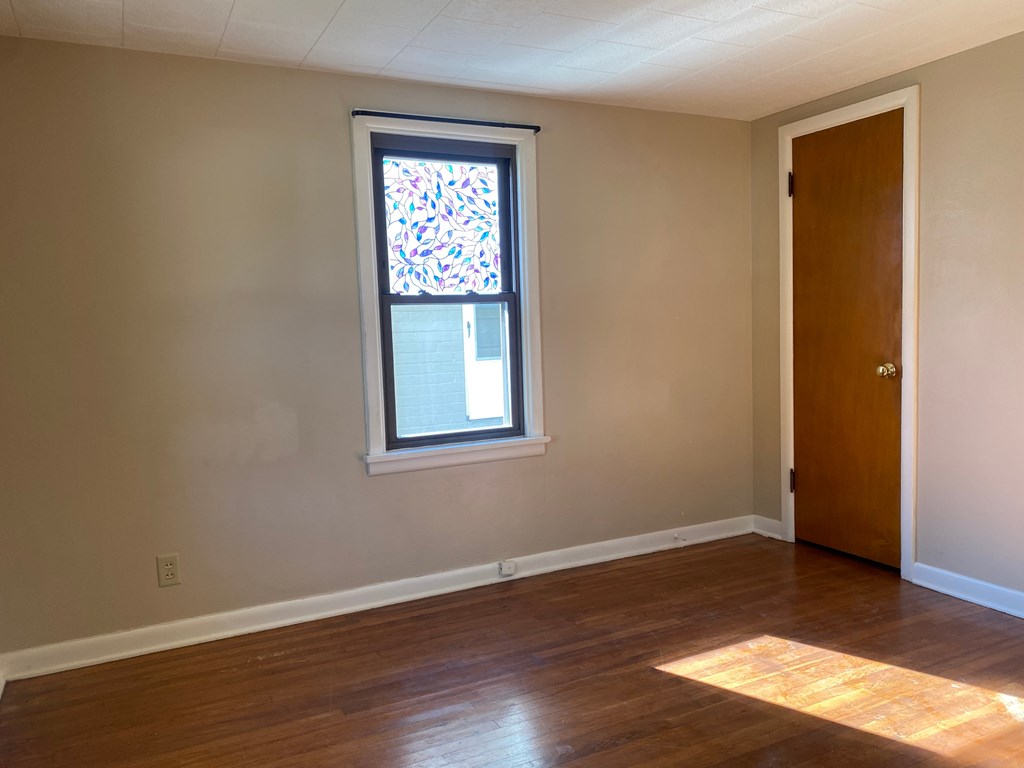 A room with a wooden floor and a stained glass window.