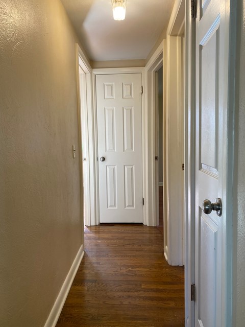 A long hallway with a white door at the end.