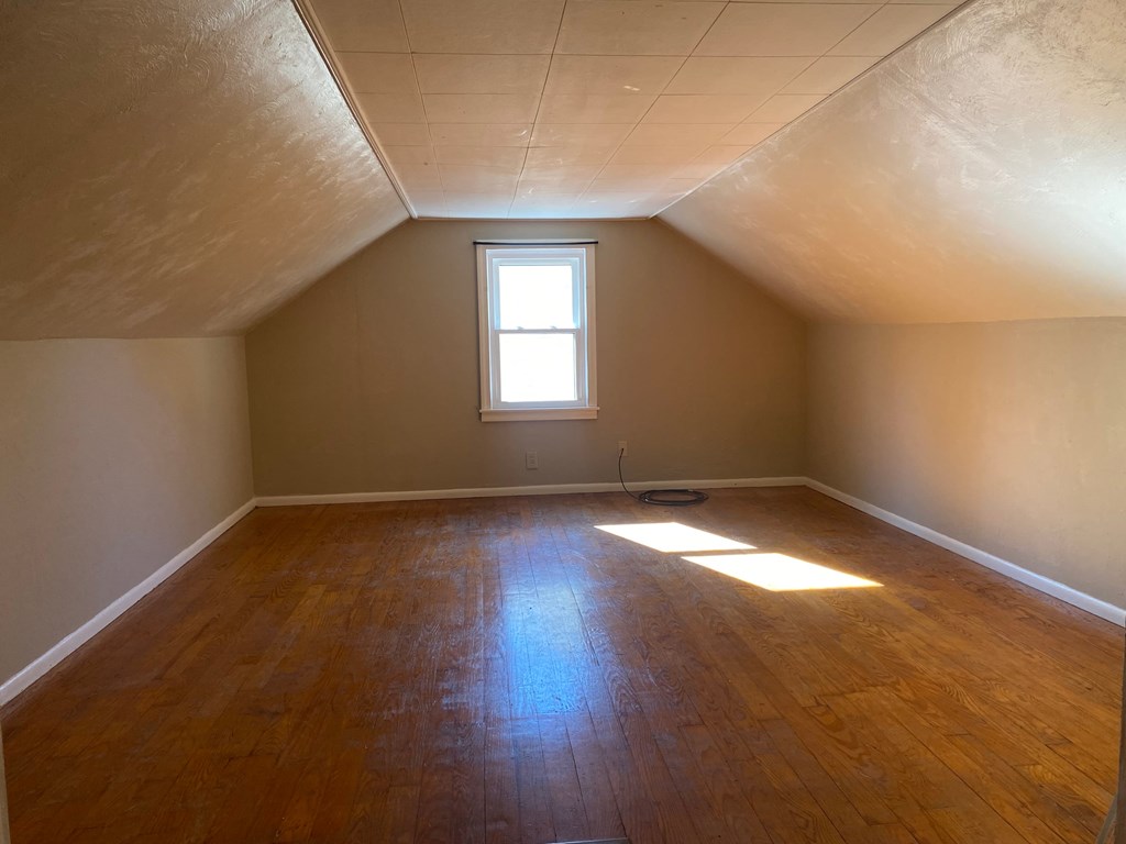 A room with wooden floors and a window letting in sunlight.