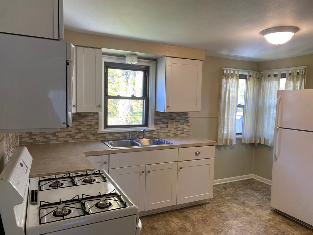 A kitchen with a white stove and cabinets.