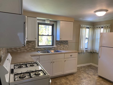 A kitchen with a white stove and cabinets.