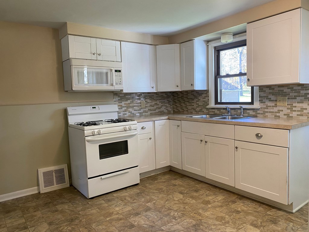 A kitchen with a white stove and cabinets.