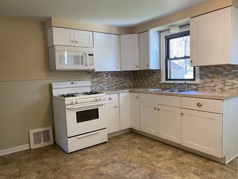 A kitchen with a white stove and cabinets.