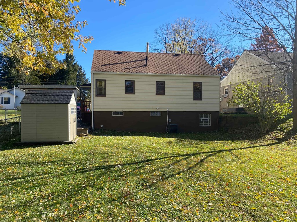 A house with a brown roof and a shed in the foreground.