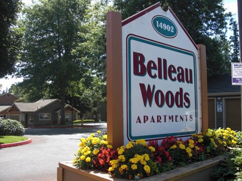 A sign for Belleau Woods Apartments is in front of a building.