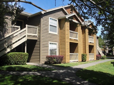 A brown wooden apartment building with a balcony on the second floor.