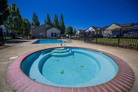 A small fountain in the middle of a brick pool.