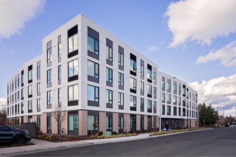 A modern white building with black windows and a black car parked in front.
