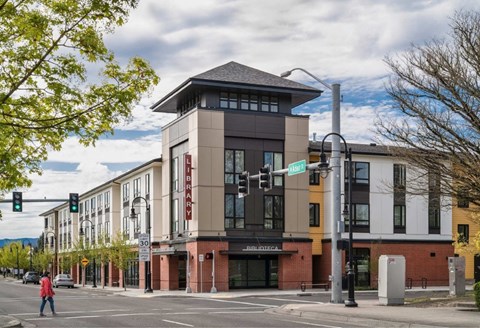 A street view of a building with a pedestrian crossing the road.