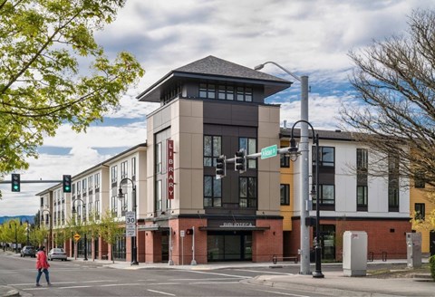 A street view of a building with a pedestrian crossing the road.