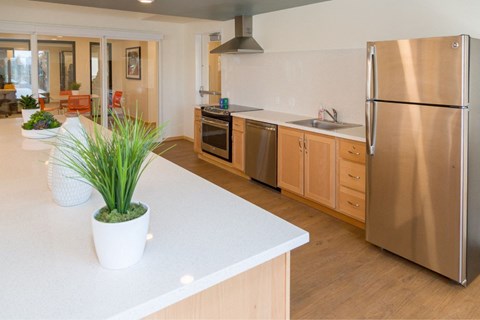 A kitchen with a white counter top and a stainless steel refrigerator.