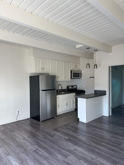 A kitchen with a refrigerator, microwave, and cabinets.