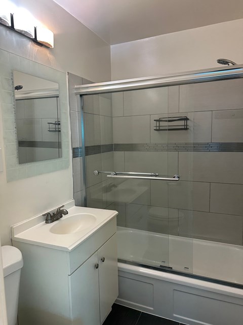 A white bathroom with a sink, toilet, and shower.