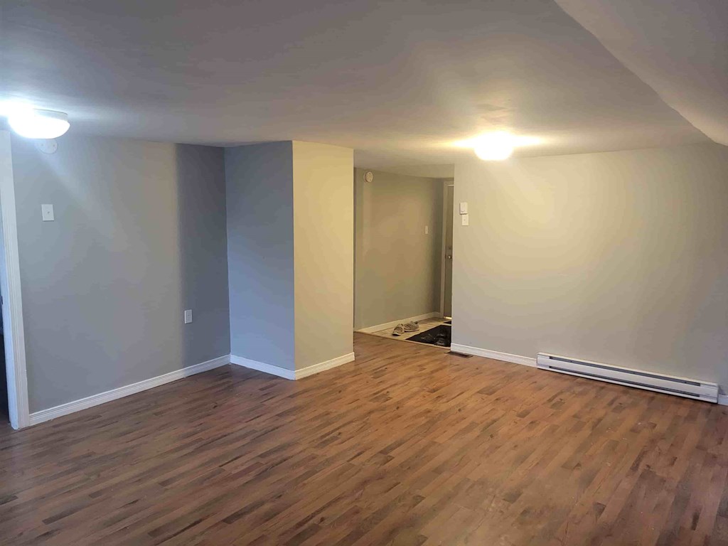 A room with wooden flooring and a doorway leading to another room.