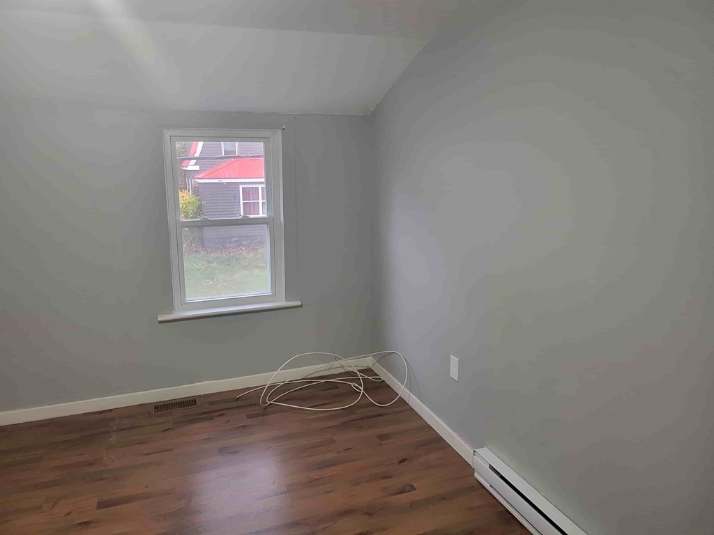 A room with a window and a wooden floor.
