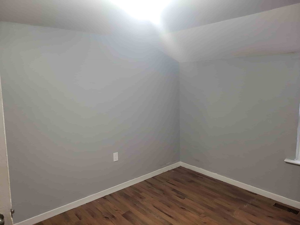 A room with wooden flooring and white walls.