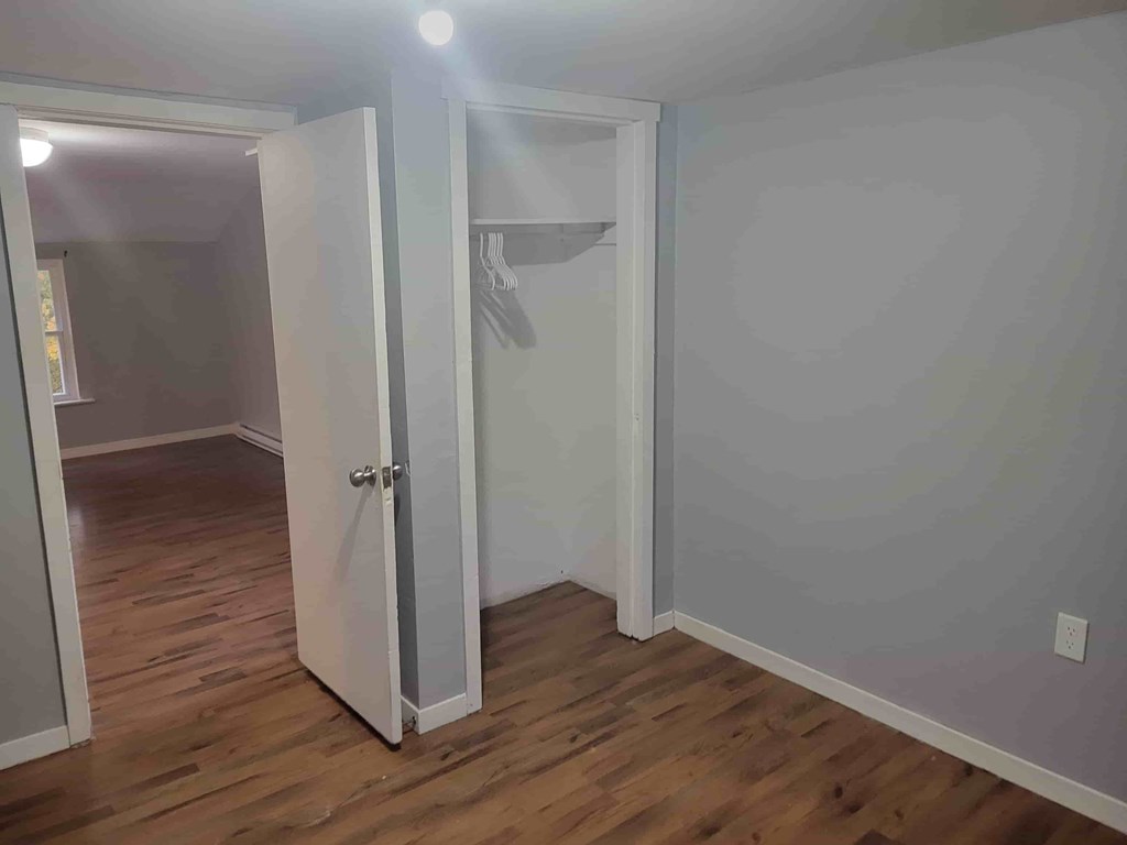 A room with a white door and wooden flooring.