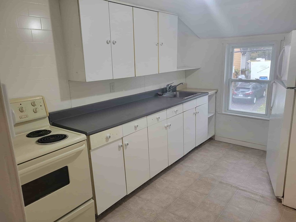 A kitchen with white cabinets and a black countertop.