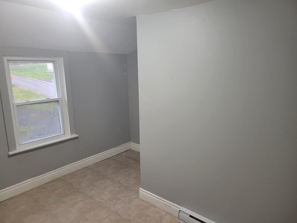 A room with a window and a wall painted in a light grey color.