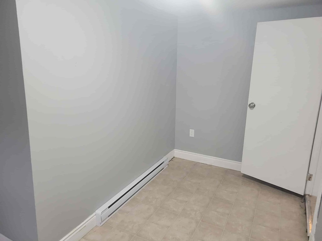 A room with a white door and a grey wall.
