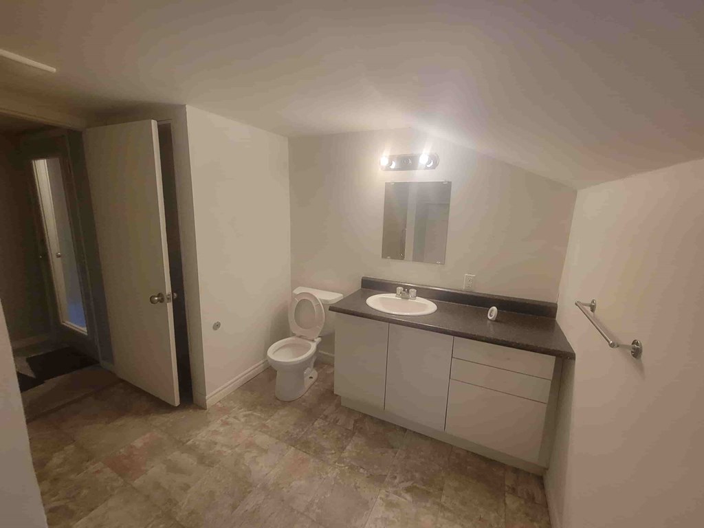 A bathroom with a toilet, sink, and mirror.