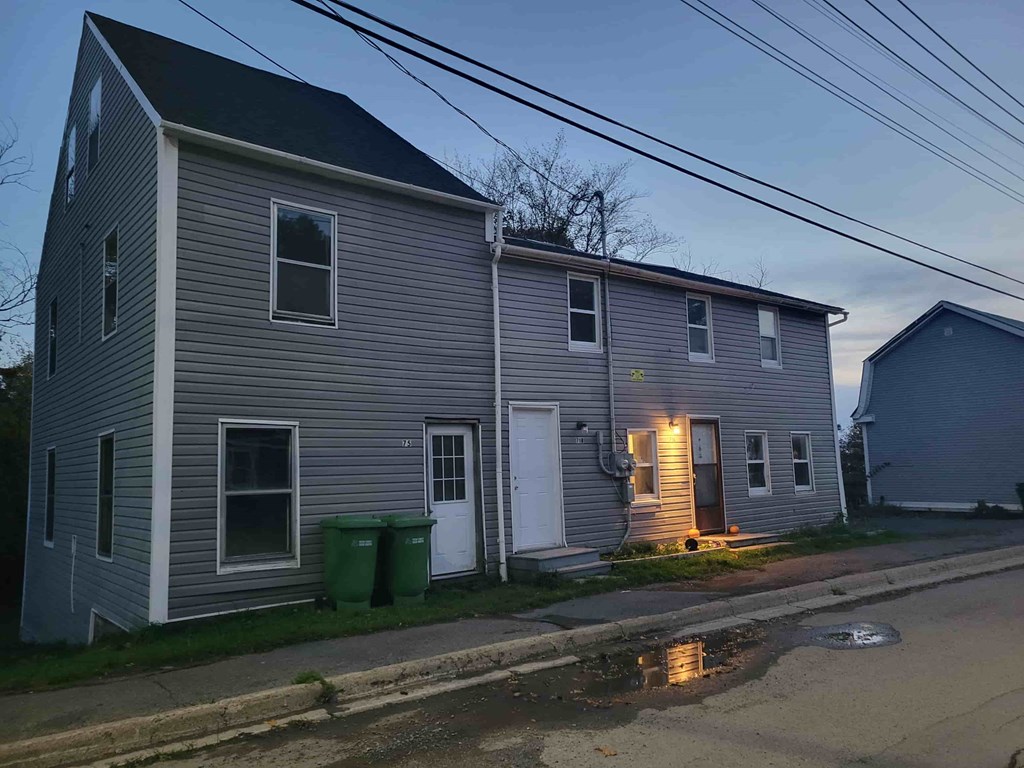 A house with a grey siding and a white door is shown.
