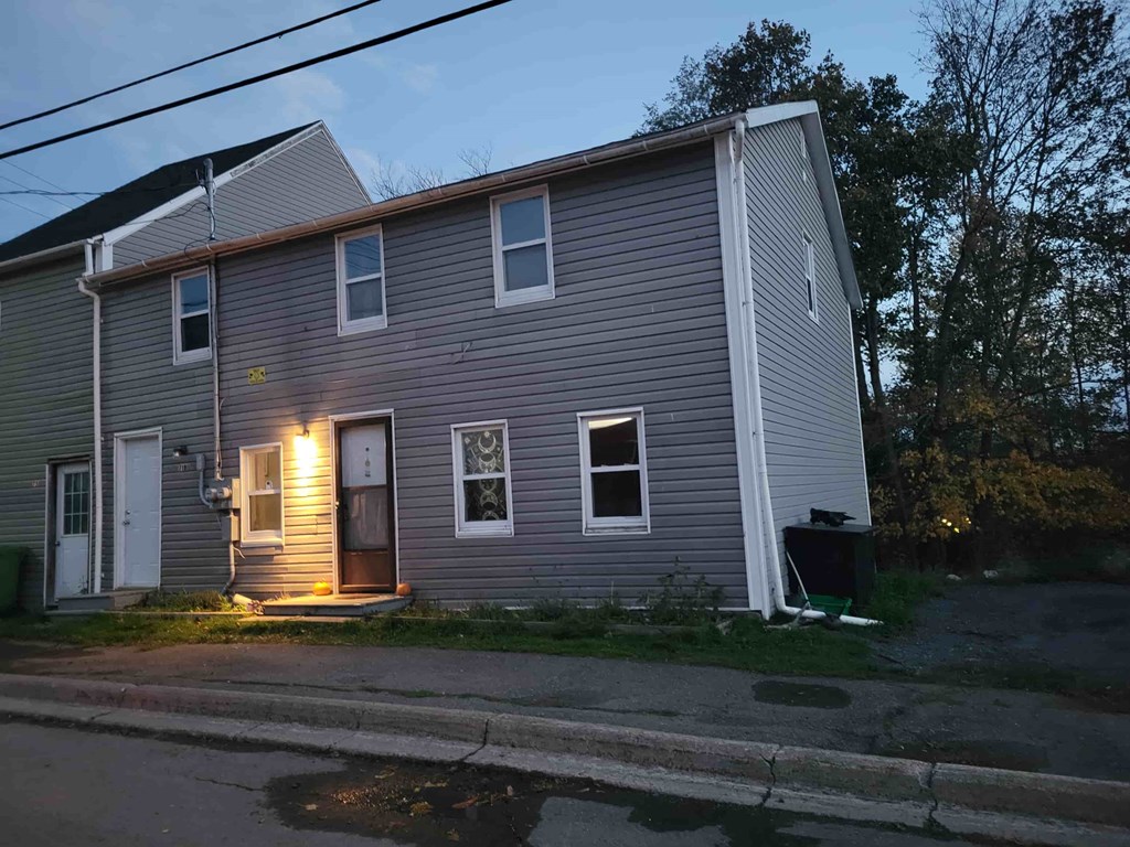 A house with a grey siding and a white door is shown.
