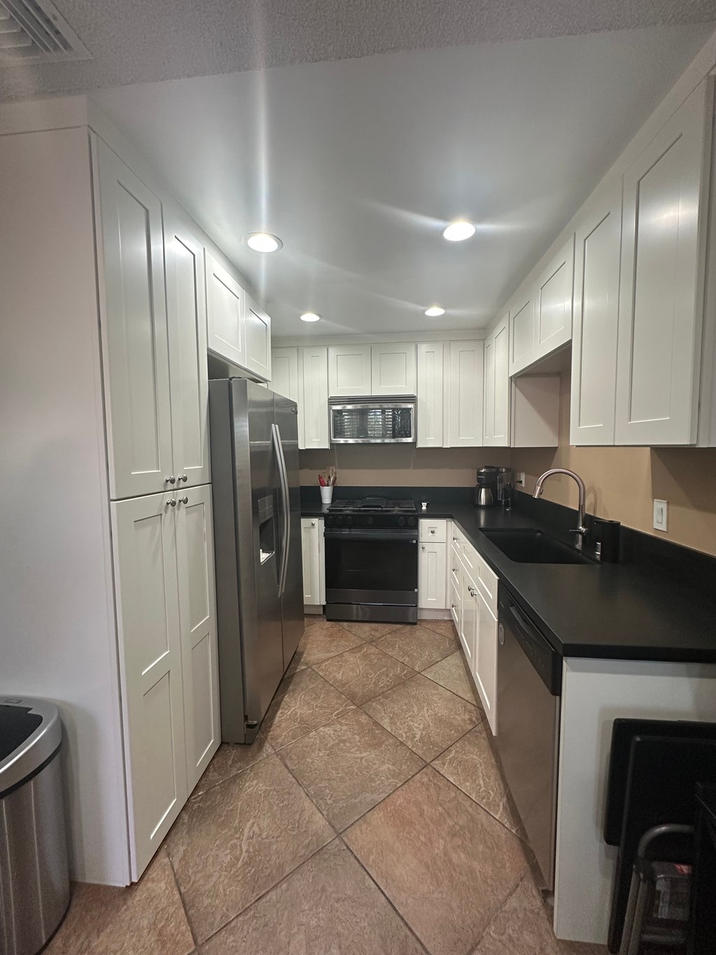 A kitchen with white cabinets and black countertops.