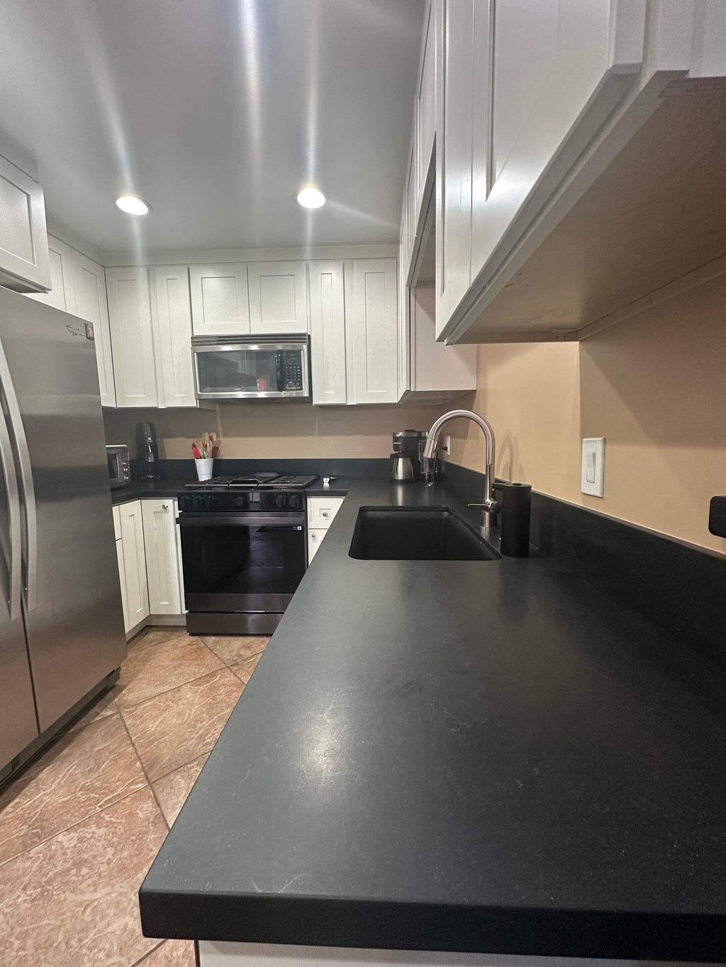 A kitchen with black countertops and stainless steel appliances.