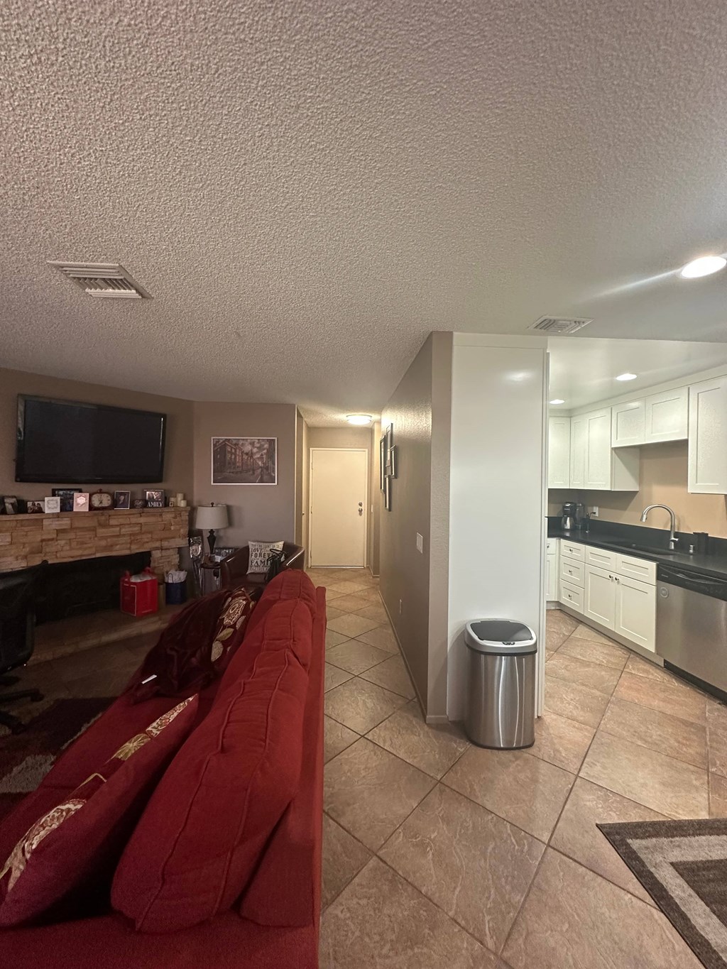 A red couch sits in a living room with a fireplace and a television.