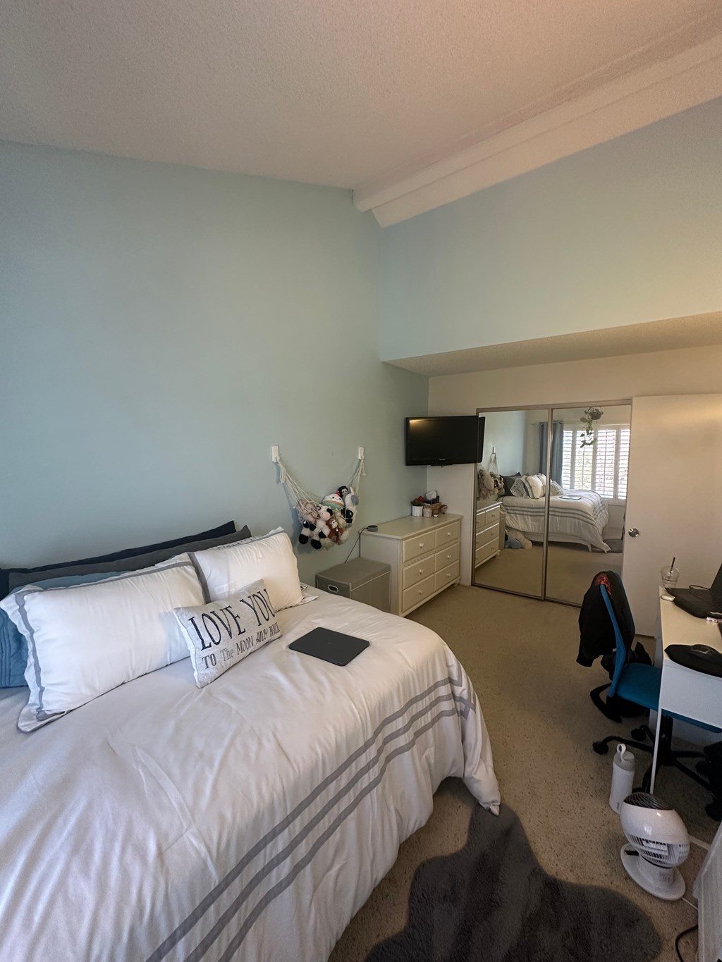 A bedroom with a large bed and a TV on the wall.